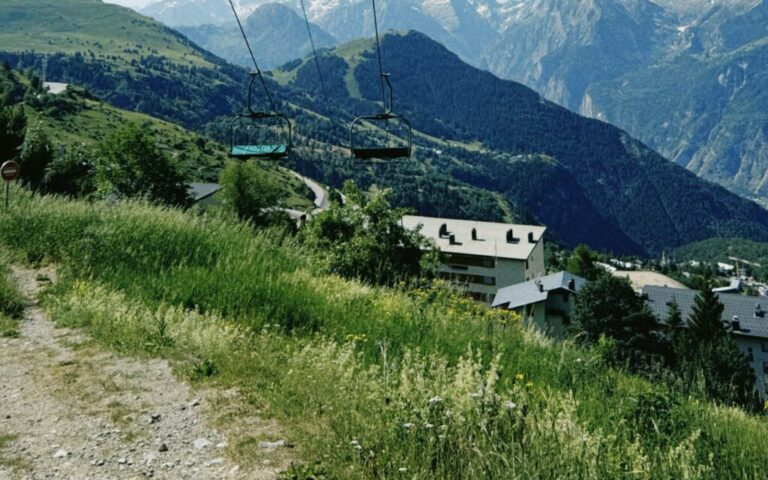 Is mountain biking replacing skiing? Empty chairlift over green summer slopes and snowy peaks