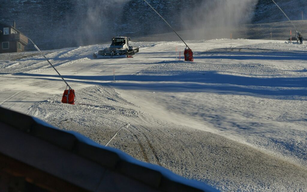 Snow cannons making artificial snow on a ski slope with little natural snow